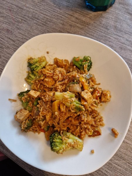 Teller mit gebratenen Mie-Nudeln, Gemüse und Tofu auf dem Tisch