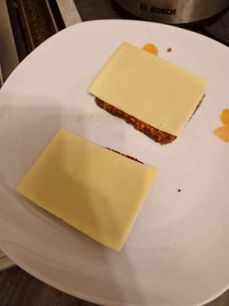 Zwei Scheiben Vollkornbrot mit je einer Scheibe Butterkäse auf einem Teller