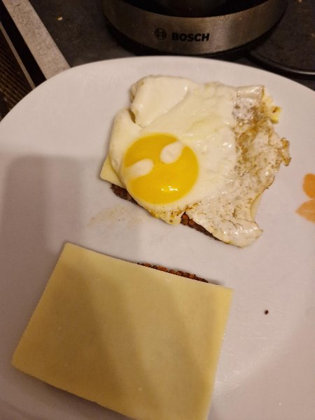 Spiegelei auf Vollkornbrot mit Käse, daneben eine Brotscheibe mit Käse